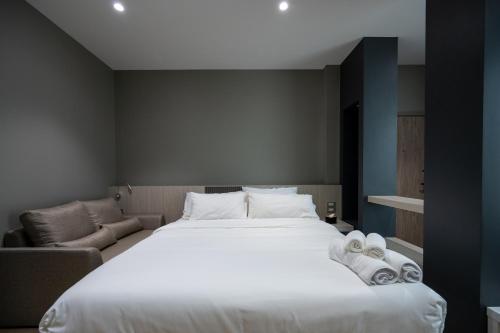 a bedroom with a large white bed and a couch at ซิตี้วรรณ ราชบุรี in Ratchaburi