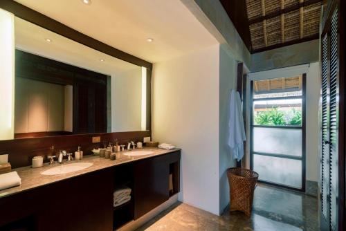 a bathroom with two sinks and a large mirror at REVĪVŌ Wellness Resort Nusa Dua Bali in Nusa Dua