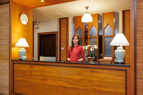 a woman standing behind a reception desk at Rimping Village in Chiang Mai