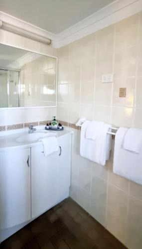 a bathroom with a sink and a mirror and towels at Hotel Forster in Forster