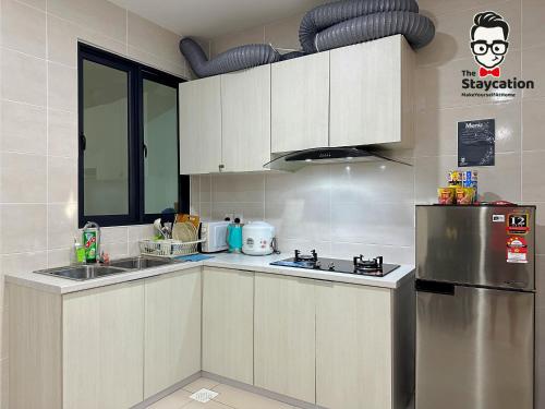a kitchen with white cabinets and a stainless steel refrigerator at Staycation Homestay 14 P Residence kuching condo in Kuching