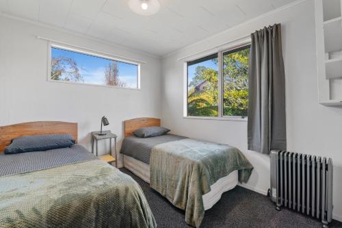 une chambre avec deux lits et deux fenêtres dans l'établissement Serenity Lakehouse - Rotorua Holiday Home, à Rotorua