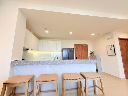 a kitchen with a counter with four stools at Homie's The Glory Apartment in Thu Dau Mot