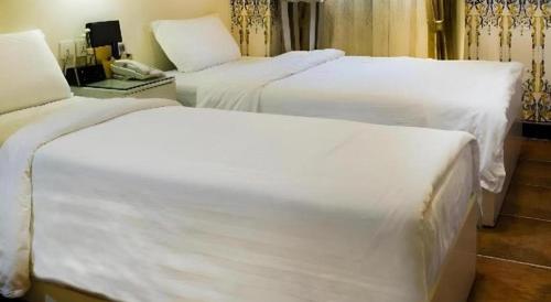 two beds in a hotel room with white sheets at Happy Family Hotel in Macau