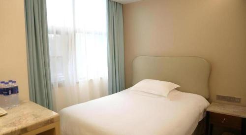 a bedroom with a white bed and a window at Leisurely Hotel Shenzhen in Shenzhen