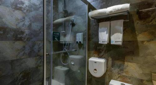 a bathroom with a glass shower stall with a toilet at Leisurely Hotel Shenzhen in Shenzhen