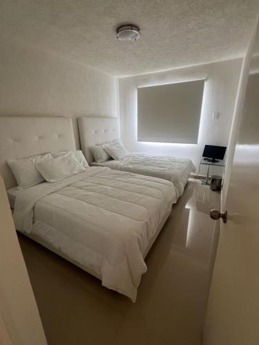 Una cama blanca grande en una habitación con ventana. en Casa Flamingo 3 Recamaras, 3 Baños completos, en Ixtapa