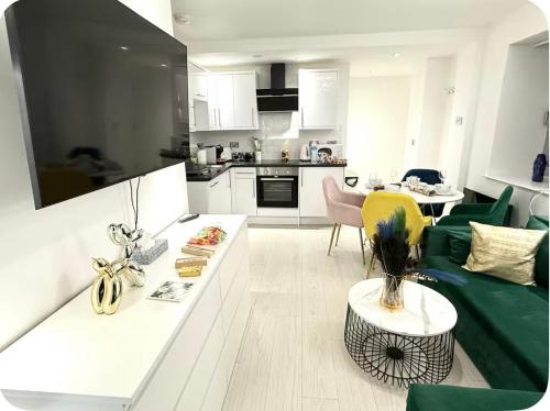 a living room with a green couch and a kitchen at Winners of 2025 traveller Award, Elegant two bedroom city central apartment with Netflix & WiFi in Leeds