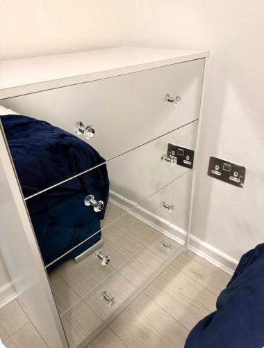 a cabinet with a blue cushion sitting in a room at Winners of 2025 traveller Award, Elegant two bedroom city central apartment with Netflix & WiFi in Leeds