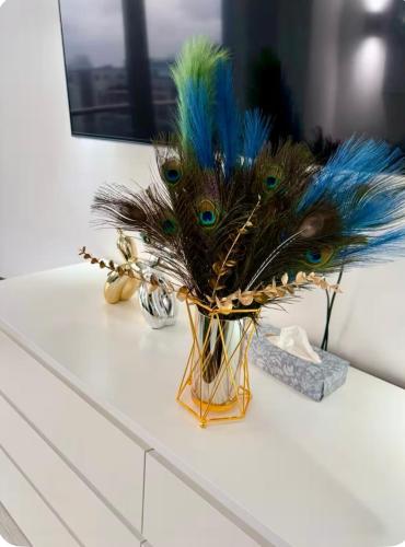 a vase with peacock feathers on top of a counter at Winners of 2025 traveller Award, Elegant two bedroom city central apartment with Netflix & WiFi in Leeds