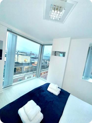 a bedroom with a blue bed with a large window at Winners of 2025 traveller Award, Elegant two bedroom city central apartment with Netflix & WiFi in Leeds