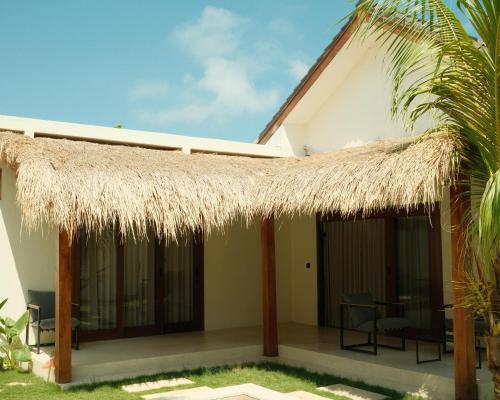 a villa with a thatched roof and a patio at Villa Sundara 2BR Private Pool in Mantaak