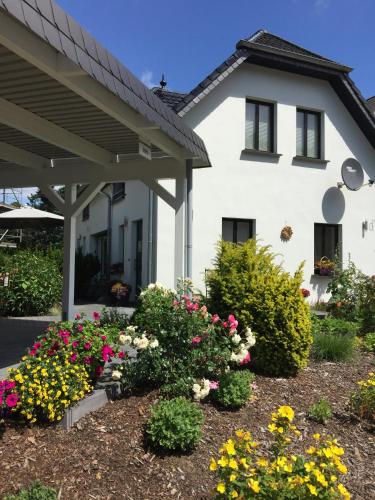 a white house with flowers in front of it at Röblinseeterrassen in Fürstenberg-Havel