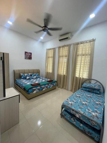 a bedroom with two beds and a ceiling fan at KTL Homestay in Kuantan