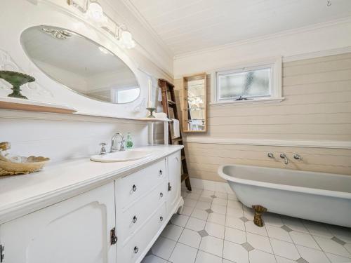 une salle de bain blanche avec une baignoire et un lavabo dans l'établissement Broughton Cottage, à Katoomba