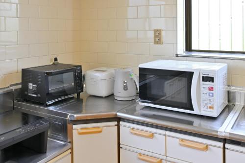 a kitchen with a microwave and a toaster oven at 間 はざま in Shodoshima