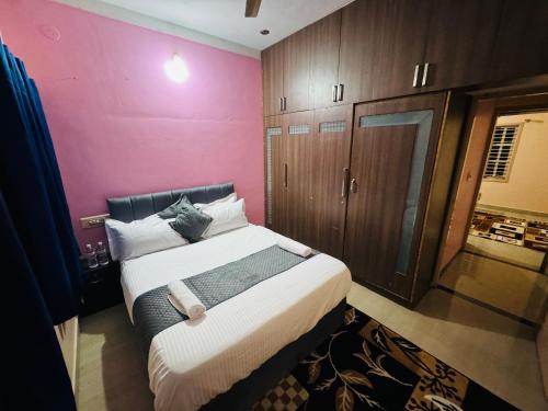 a bedroom with a large bed with a pink wall at LUXE Premium homestay in Mysore