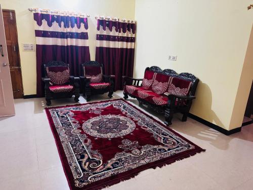 a living room with three chairs and a red rug at LUXE Premium homestay in Mysore