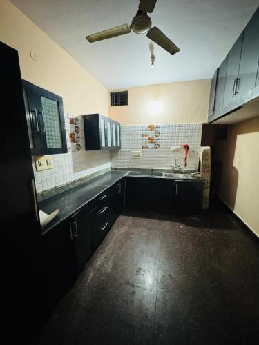 a kitchen with black cabinets and a ceiling fan at LUXE Premium homestay in Mysore