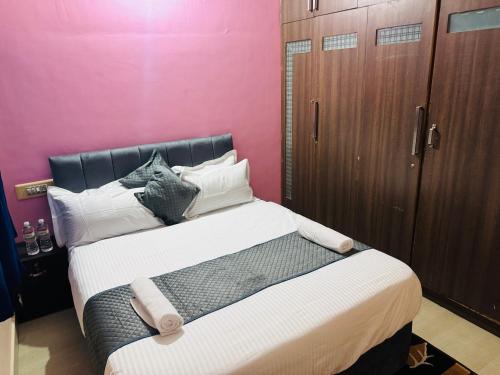 a bedroom with a large bed and a pink wall at LUXE Premium homestay in Mysore