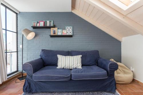 a blue couch in a living room with a brick wall at Casas da Formosa - Casa do Postigo in Tavira