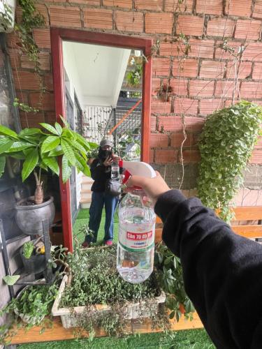 a person holding a bottle of water in front of a mirror at Hoa dalathouse in Da Thanh