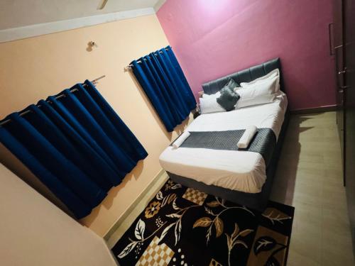 a small bedroom with a bed with blue curtains at LUXE Premium homestay in Mysore