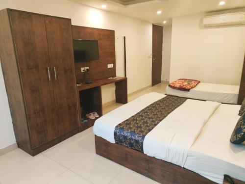a bedroom with two beds and a cabinet with a television at Hotel TEJ PALACE NEAR IGI AIRPORT in New Delhi