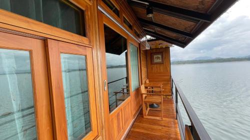 a wooden boat with windows on a body of water at The Floating Lake House in Ban Pracham Mai Bon
