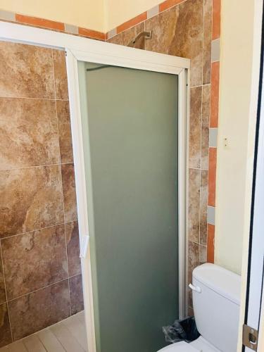 a bathroom with a shower door and a toilet at Hotel Estancia Don Roberto San Blas in San Blas