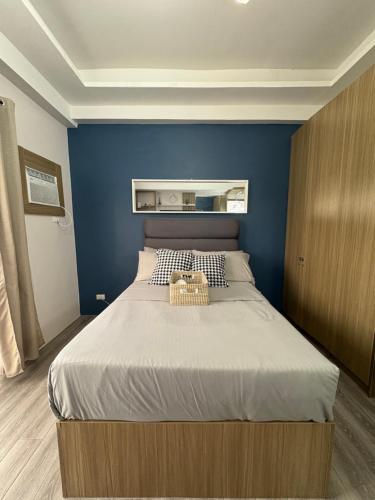 a bedroom with a large bed with a blue wall at Amani 311 Suites - Double bed with Single Pull Out Bed in Pusok