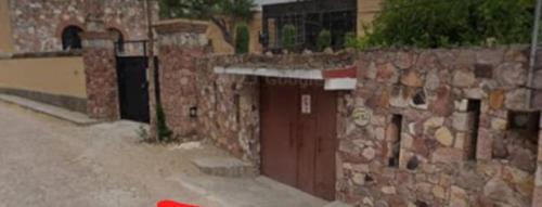 a stone building with a brown door and a wall at Residencia a 15min de San Miguel de Allende p/20 personas in Atotonilco