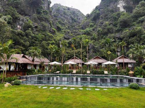 a resort with a swimming pool with mountains in the background at Tam Coc Golden Fields in Ninh Binh