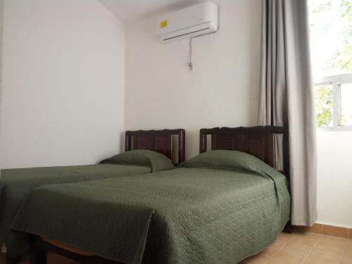two beds with green sheets in a room with a window at Paz en el Mar in Bahías de Huatulco