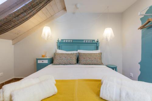 a bedroom with a large bed with a blue headboard at Casas da Formosa - Casa do Postigo in Tavira