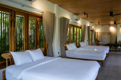 two white beds in a room with windows at Tổ Boutique Garden in La Gi