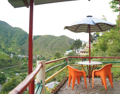 a table and chairs and an umbrella on a balcony at The Mud house, Mussoorie in Mussoorie