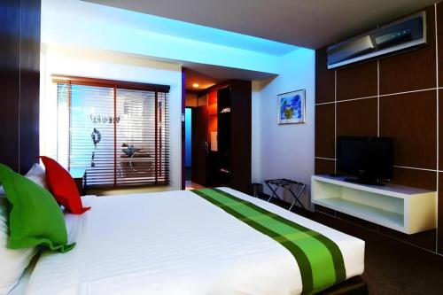 a bedroom with a large bed and a television at V-One Hotel Korat in Nakhon Ratchasima