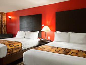 a hotel room with two beds and a red wall at Days Inn by Wyndham Henryetta in Henryetta