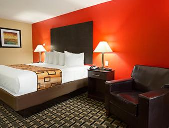 a hotel room with a bed and a chair at Days Inn by Wyndham Henryetta in Henryetta