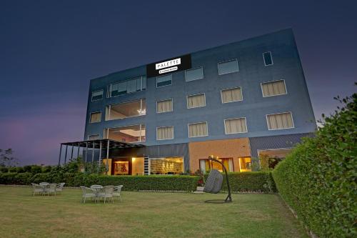 a hotel with tables and chairs in front of a building at Palette Hotel and Resort Bareilly Formerly Bellazio Suites in Bareilly