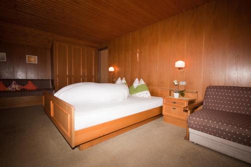 a bedroom with a white bed and a chair at Garni Reider in Meltina