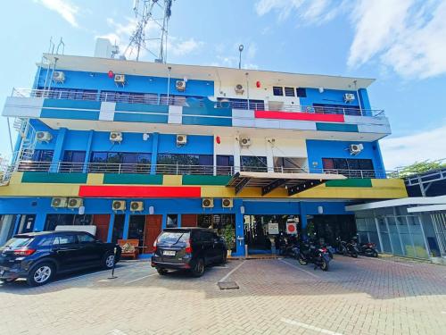 a large blue building with cars parked in front of it at YUTAKA INN Global Juanda Sidoarjo in Kalangan