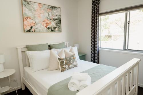 une chambre avec un lit blanc avec des oreillers et une fenêtre dans l'établissement Potager House, à Carool