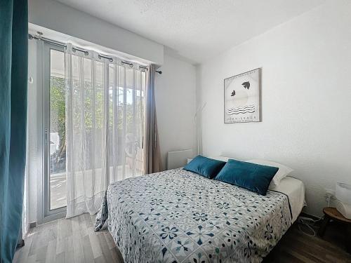 une chambre avec un lit avec des oreillers bleus et une fenêtre dans l'établissement La Maison Bleue, Evasion tranquille, à La Grande Motte