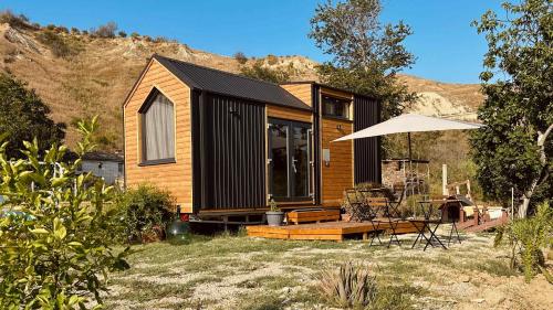 a small wooden house with a table and an umbrella at La Casa Errante 1 by Tiny Away in Castilenti