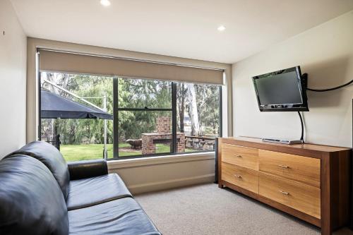 a living room with a couch and a large window at The Treehouse in Moama