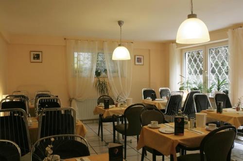 uma sala de jantar com mesas, cadeiras e janelas em Hotel Eilenriede em Hanôver