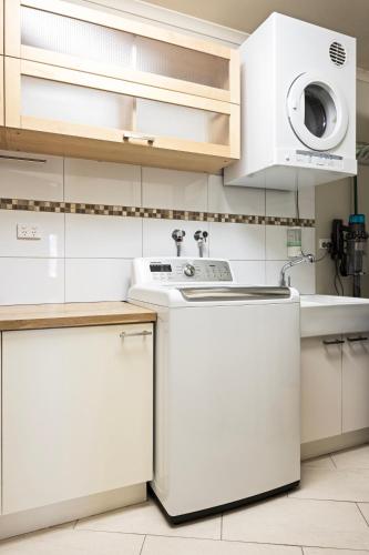 a white kitchen with a washer and dryer at The Treehouse in Moama