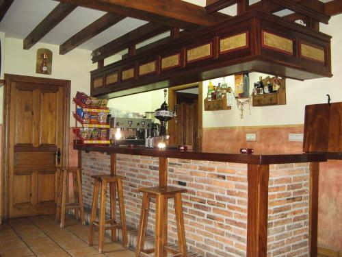 a bar with wooden stools and a brick wall at Posada El Hoyal in Pesaguero-La Parte
